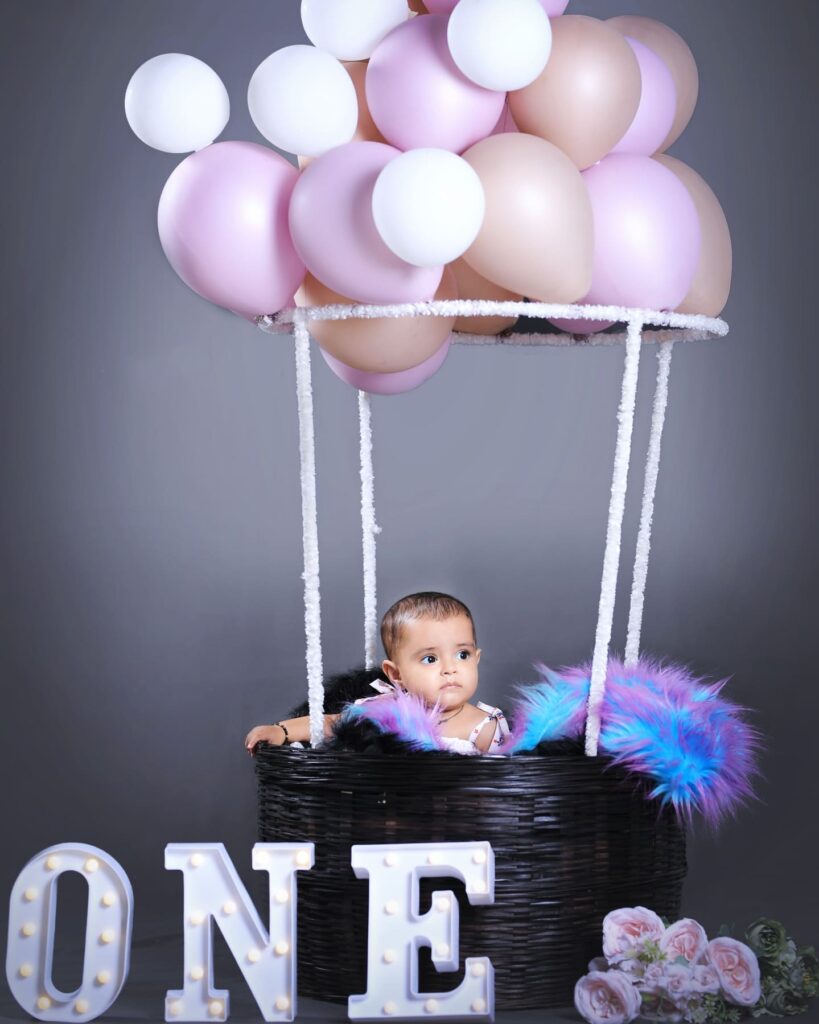 Adorable baby enjoying a birthday party with balloons